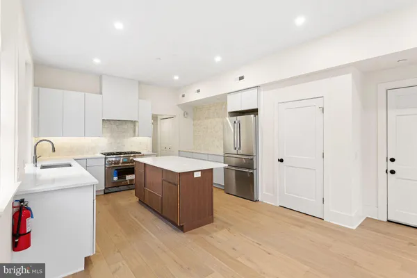 a kitchen with stainless steel appliances granite countertop a stove top oven a sink dishwasher and a refrigerator with wooden floor