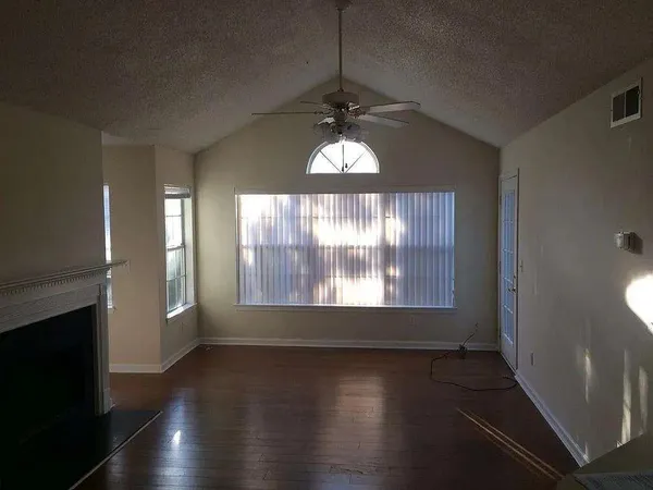 an empty room with wooden floor and windows