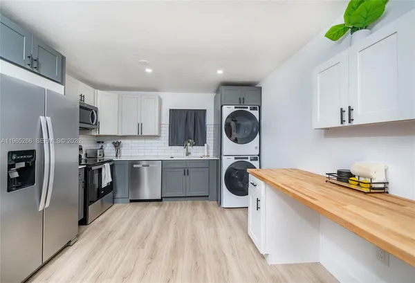 a kitchen with a refrigerator a stove top oven a sink dishwasher and white cabinets with wooden floor