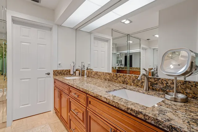 a bathroom with a granite countertop double vanity sink and a mirror