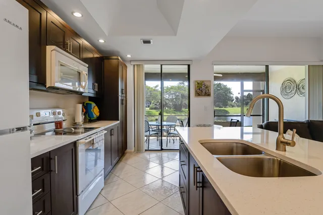 a kitchen with kitchen island granite countertop a sink and a stove top oven