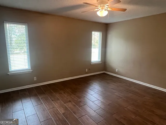 an empty room with wooden floor and windows