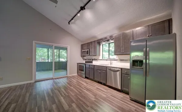 a kitchen with stainless steel appliances granite countertop a refrigerator a sink dishwasher a stove and white countertops with wooden floor