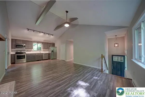 a view of a kitchen center island wooden floor and stainless steel appliances