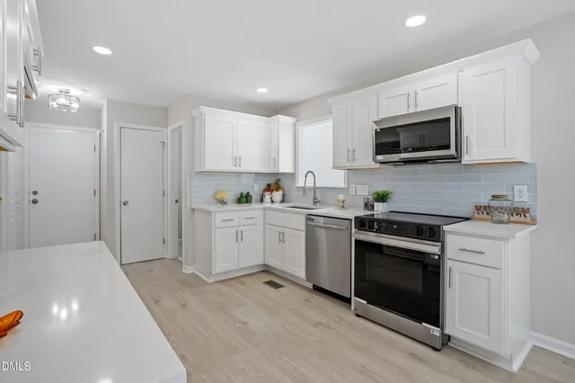 a kitchen with white cabinets stainless steel appliances and sink