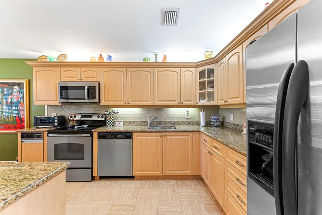 a kitchen with stainless steel appliances granite countertop a stove top oven a sink dishwasher a dining table and chairs with wooden floor