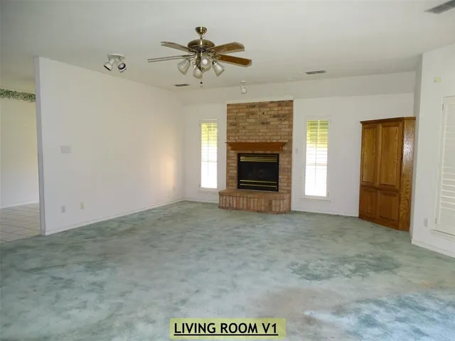 an empty room with windows and fireplace