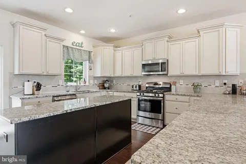 a kitchen with stainless steel appliances granite countertop a stove top oven a sink a granite counter tops and a white cabinets