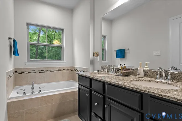 a bathroom with a granite countertop tub sink and mirror