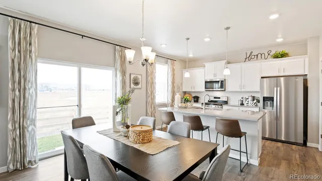 a kitchen with a dining table chairs and refrigerator