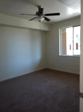 an empty room with a window and a fan