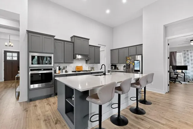 a kitchen with stainless steel appliances kitchen island granite countertop a table chairs sink and cabinets