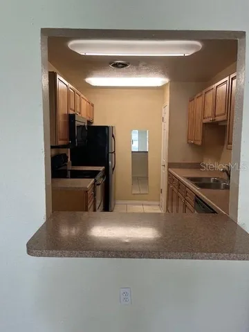 a kitchen with stainless steel appliances granite countertop a refrigerator a stove and a sink with wooden cabinets