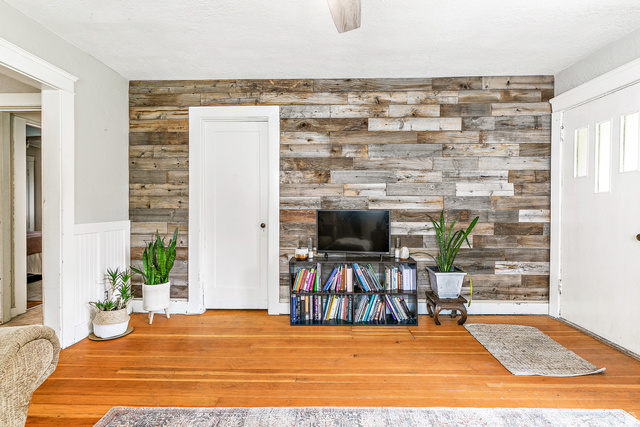 232 300 North Provo, UT 84606 - Photo 5 of 27 Living room with wooden walls, hardwood / wood-style flooring, ceiling fan, an accent wall, and a wainscoted wall