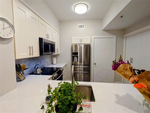 a kitchen with stainless steel appliances kitchen island granite countertop a refrigerator and a sink