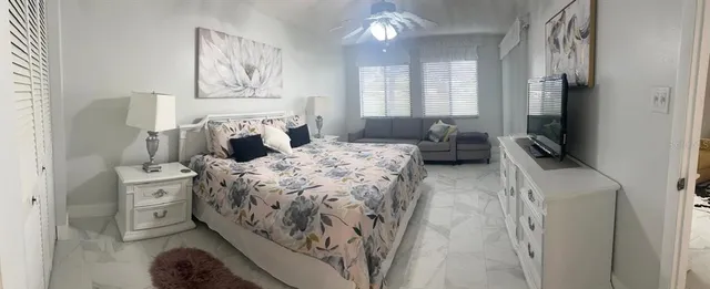 a bedroom with a large bed and a flat tv screen on dresser