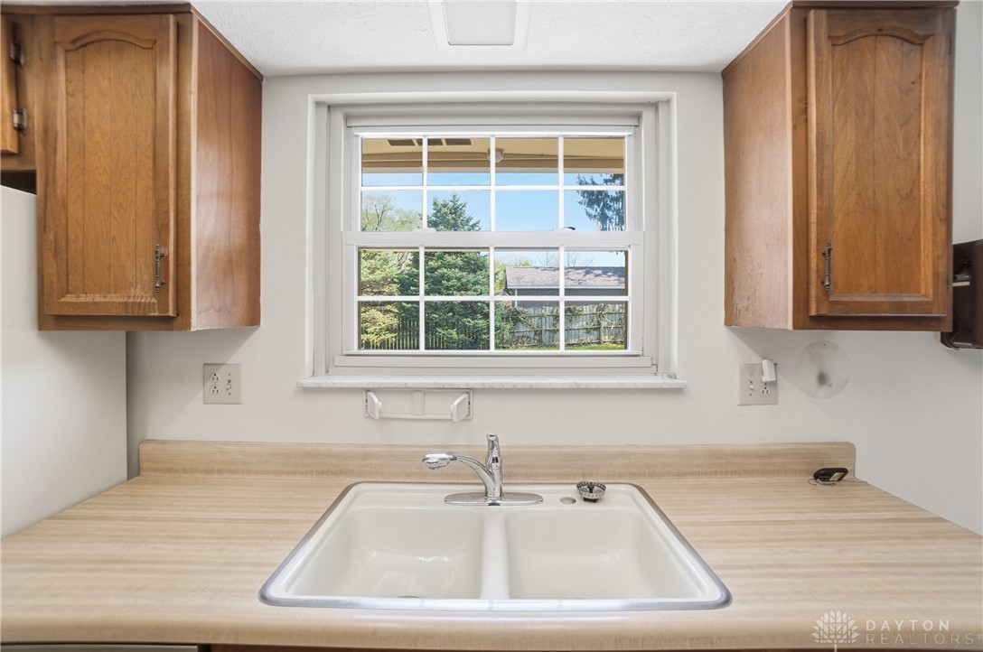 9964 Hummingbird Way Dayton, OH 45458 - Photo 18 of 57 This kitchen offers practical functionality with ample cabinetry and a window overlooking lush greenery.