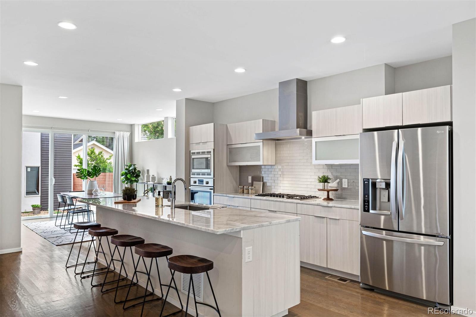 4011 Raleigh Street Denver, CO 80212 - Photo 8 of 34 a kitchen with stainless steel appliances a refrigerator a sink a stove a dining table and chairs