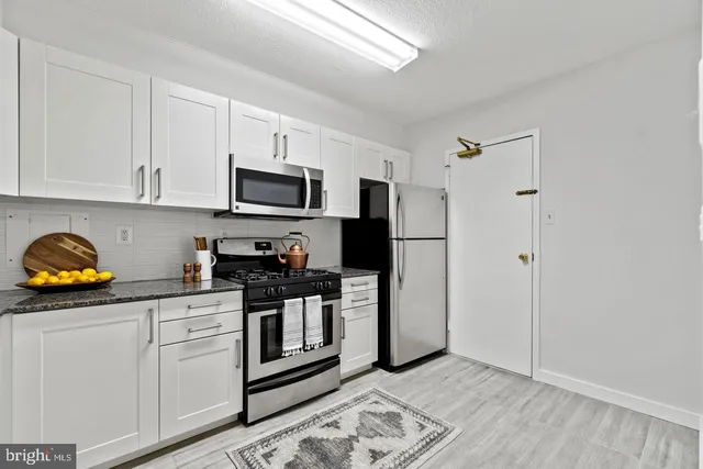 a kitchen with stainless steel appliances granite countertop a refrigerator and a stove top oven