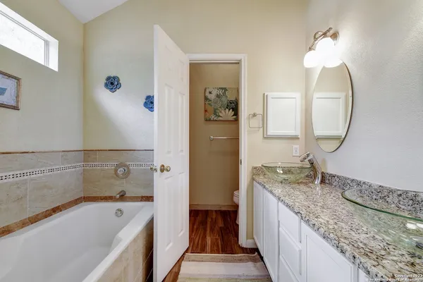 a bathroom with a granite countertop tub sink and mirror