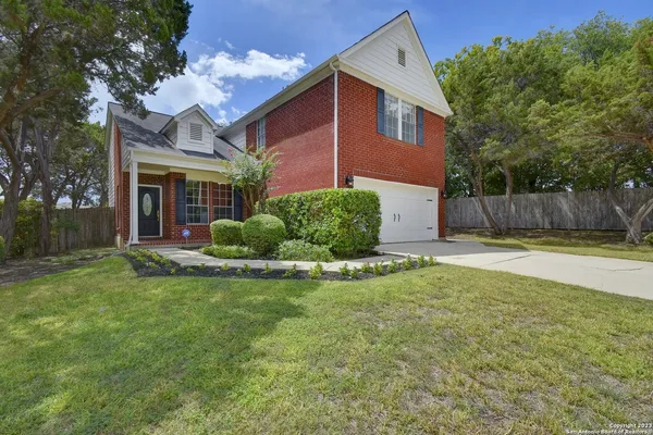 a view of a house with a yard and a large tree
