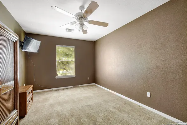 an empty room with windows and fan