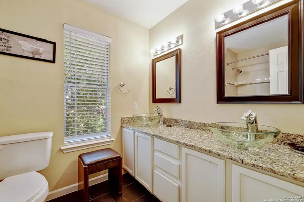 a bathroom with a toilet a sink a mirror and a window