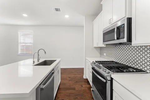 a kitchen with a sink stove and white cabinets