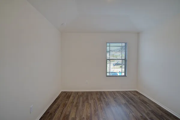 an empty room with wooden floor closet and windows