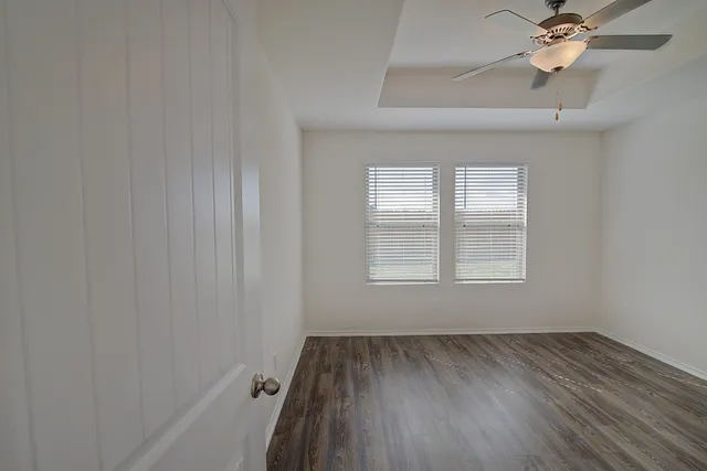 an empty room with a window and a fan