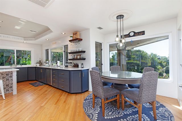 a kitchen with stainless steel appliances kitchen island granite countertop a table chairs and a wooden floor