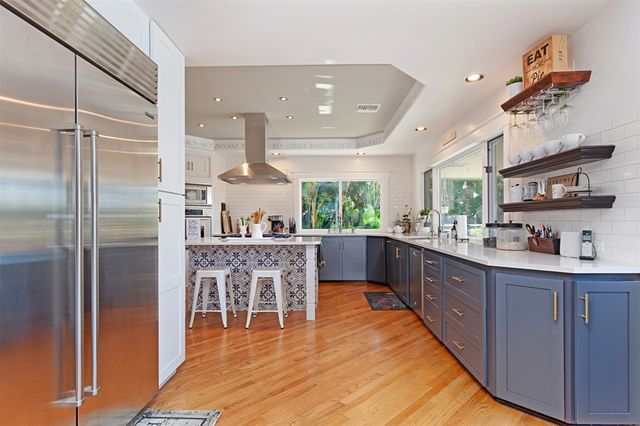 a kitchen with stainless steel appliances granite countertop a refrigerator a sink dishwasher a dining table and chairs with wooden floor