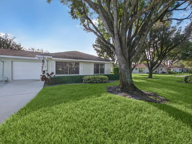 a view of a house next to a big yard and large trees