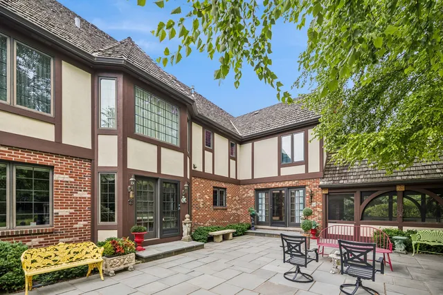 a view of a brick house with chairs and table in a patio