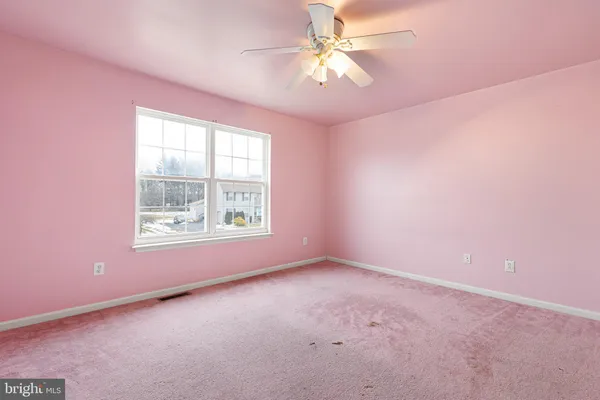 an empty room with a window and a fan