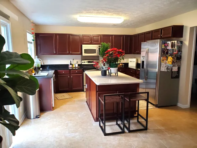 a kitchen with stainless steel appliances kitchen island granite countertop a refrigerator stove microwave and sink