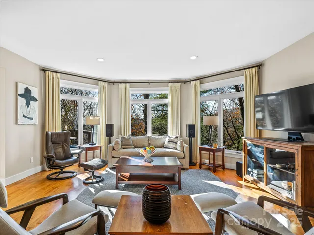 a living room with furniture a flat screen tv and large windows