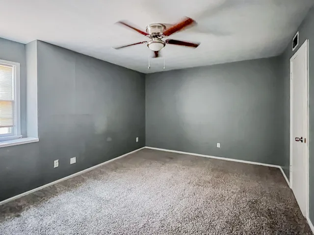 an empty room with ceiling fan and window