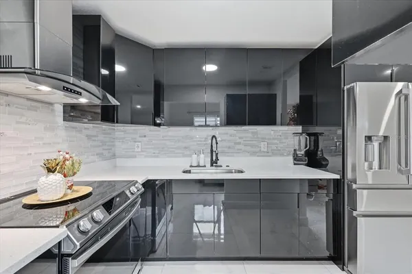 a kitchen with stainless steel appliances a sink a stove a refrigerator and cabinets