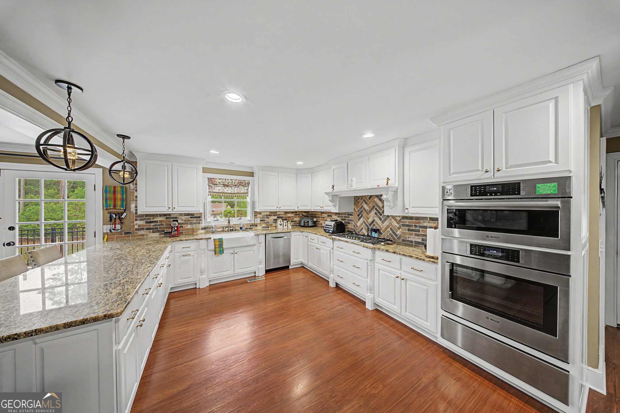 306 Holly Trail Moultrie, GA 31768 - Photo 6 of 40 a large white kitchen with stainless steel appliances granite countertop a stove a sink a refrigerator and white cabinets with wooden floor