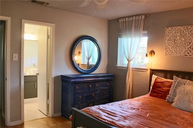 a bedroom with a bed a mirror on the dresser and a table