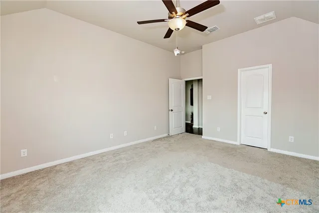 an empty room with fan walk in closet with a mirror