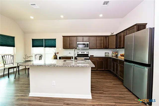 a kitchen with stainless steel appliances wooden floor and a refrigerator