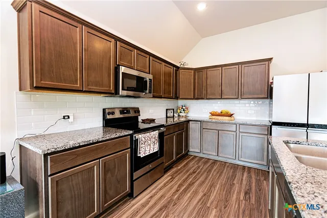 a kitchen with granite countertop wooden cabinets and a stove top oven