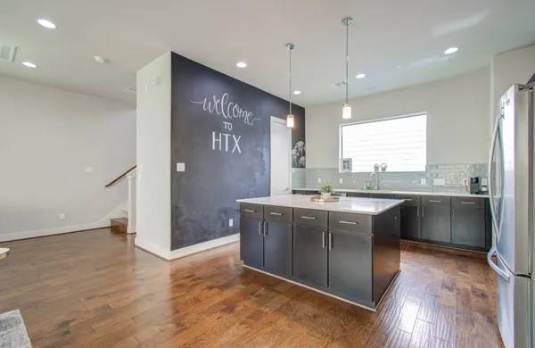 a large kitchen with stainless steel appliances granite countertop a refrigerator a sink dishwasher a stove and white countertops with wooden floor