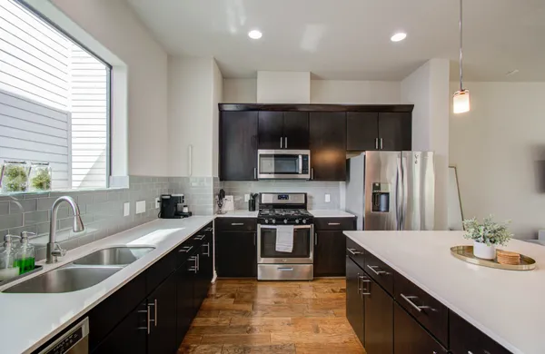 a kitchen with stainless steel appliances granite countertop a sink a stove top oven a refrigerator cabinets and a center island