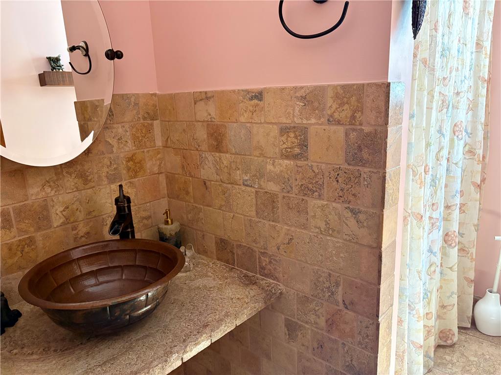 1222 Spring Road Andreas, PA 18211 - Photo 14 of 38 A vessel sink rests on stone countertops, complemented by tiled walls and an ornate mirror.