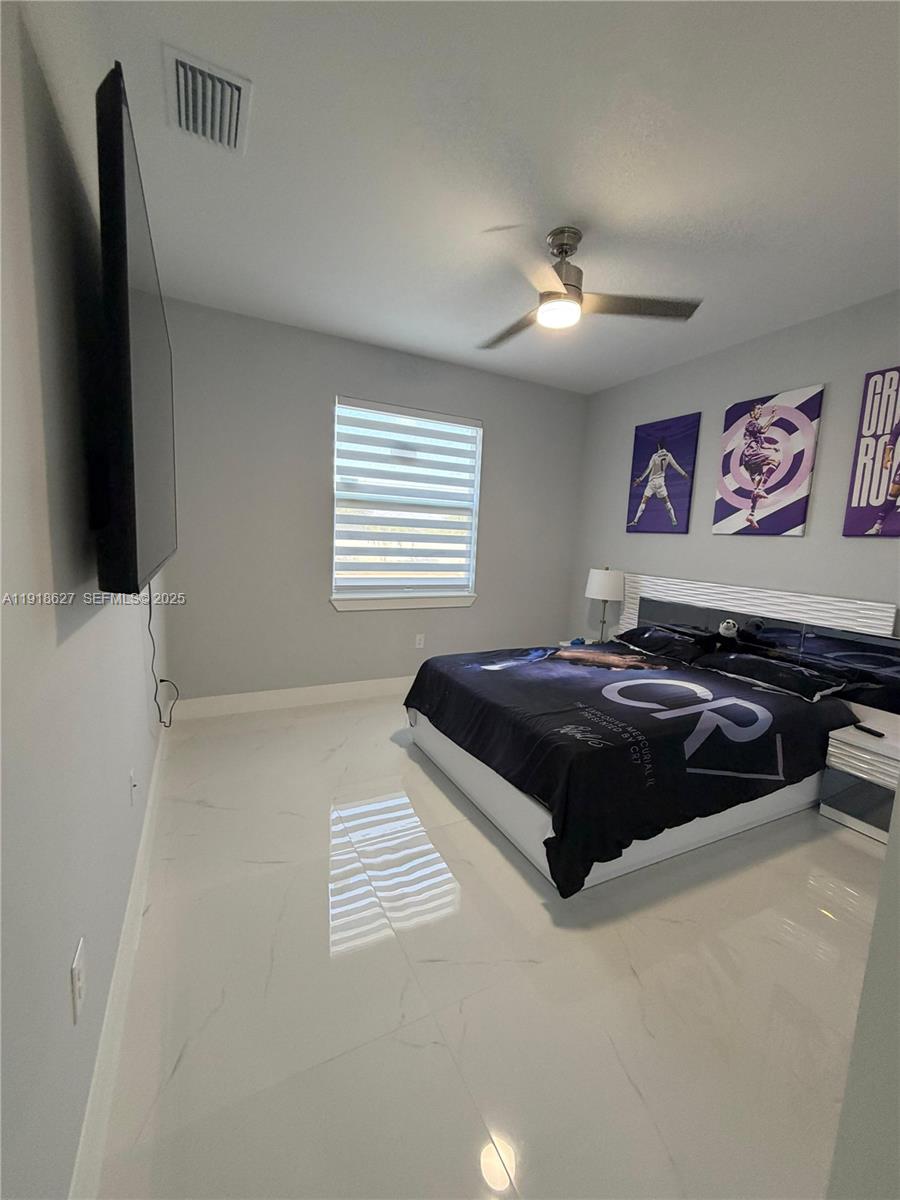 2923 22nd Street Southwest Lehigh Acres, FL 33976 - Photo 18 of 24 a bedroom with a bed and a flat screen tv
