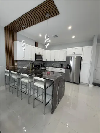 a kitchen with stainless steel appliances granite countertop a stove a sink a refrigerator and a microwave