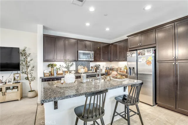 a kitchen with granite countertop stainless steel appliances a refrigerator a stove a dining table and chairs